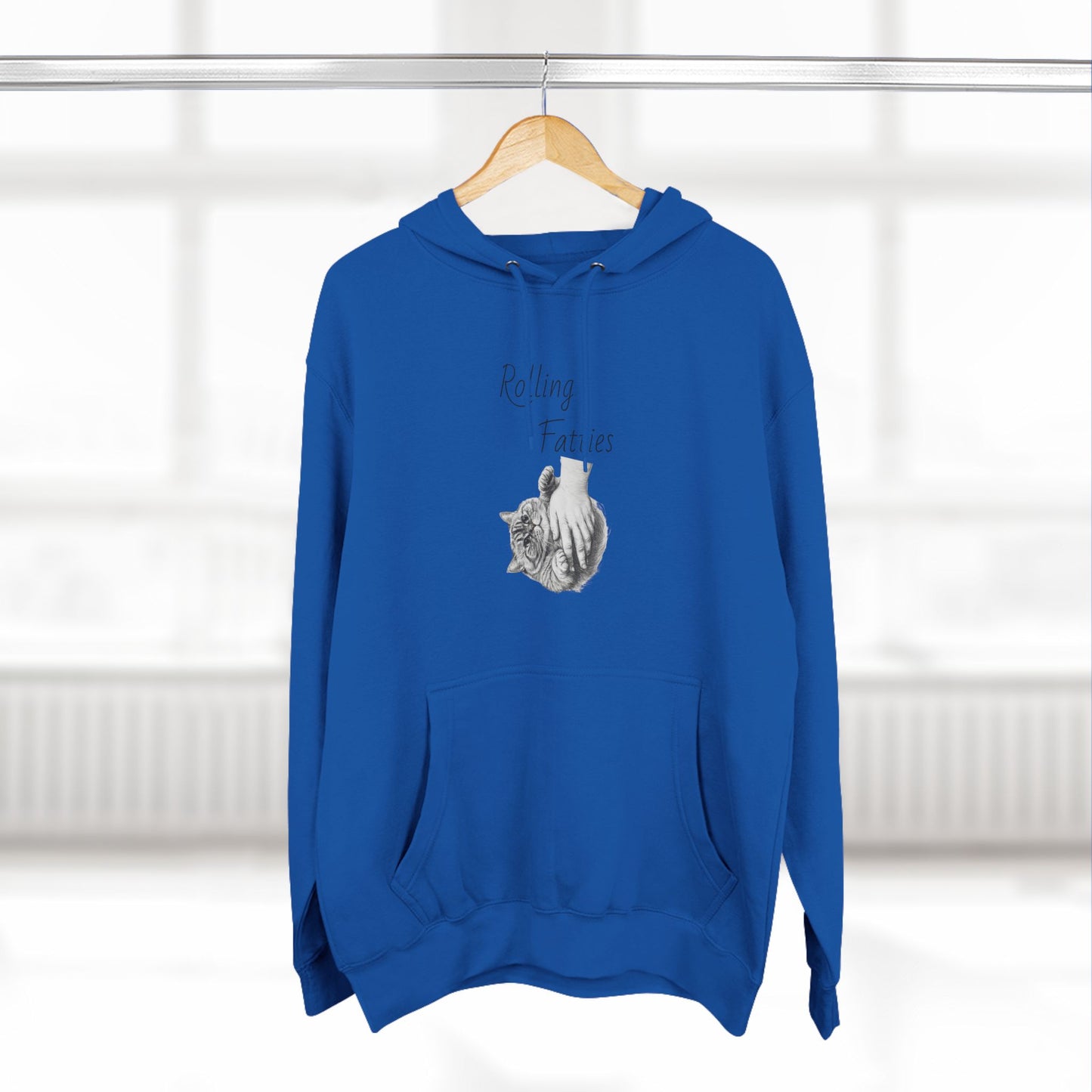 Royal blue Rolling Fatties Hoodie hanging on a wooden hanger in a bright setting. A stylish and cozy wardrobe staple.