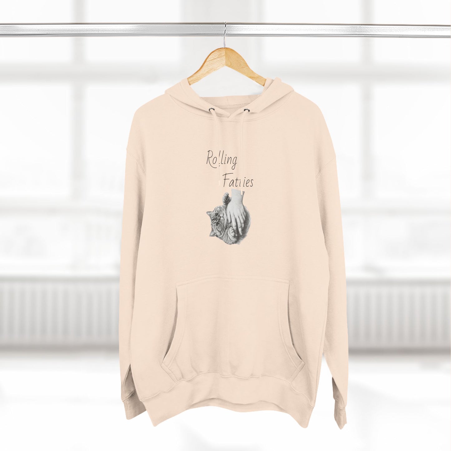 Beige Rolling Fatties Hoodie hanging on a wooden hanger in a bright room. A cozy and fashionable addition to any wardrobe.